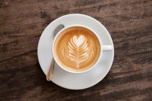 Cup of heart latte art on wood table